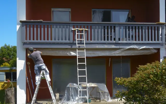 Painter on a stepladder working on an exterior wall