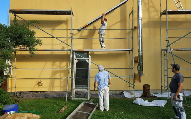Painting crew working from scaffolding on a stucco building